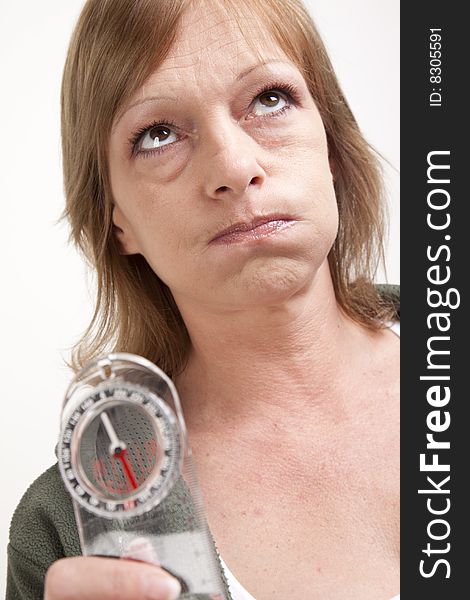 A mature adult woman showing frustration while holding up a compass. A mature adult woman showing frustration while holding up a compass.