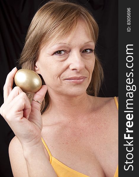 Mature woman secure in her investments symbolized by golden egg. Mature woman secure in her investments symbolized by golden egg
