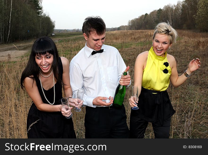 Two girls and man with wine outdoors