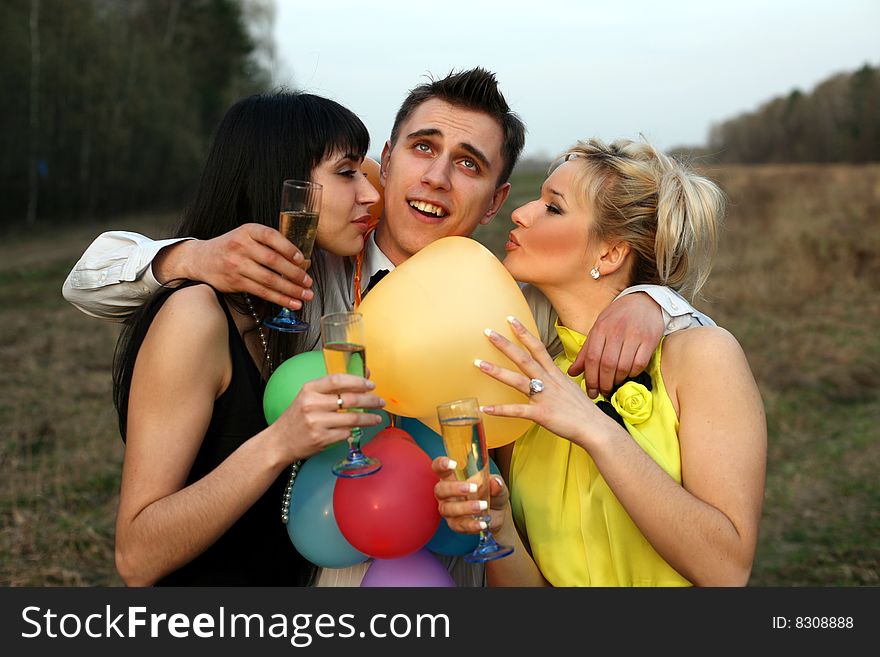 Two girl with wine kissing man outdoors. Two girl with wine kissing man outdoors