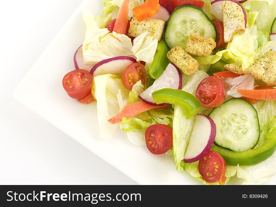 A colorful fresh garden salad in a white square bowl with white background  copy space