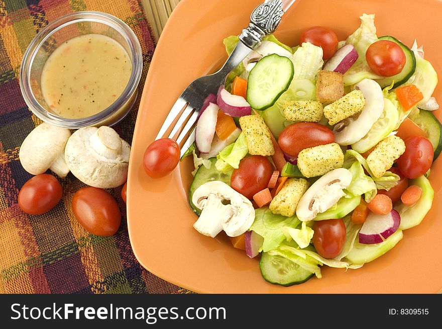 Colorful fresh garden salad with mushrooms in an orange bowl with fork  copy space. Colorful fresh garden salad with mushrooms in an orange bowl with fork  copy space