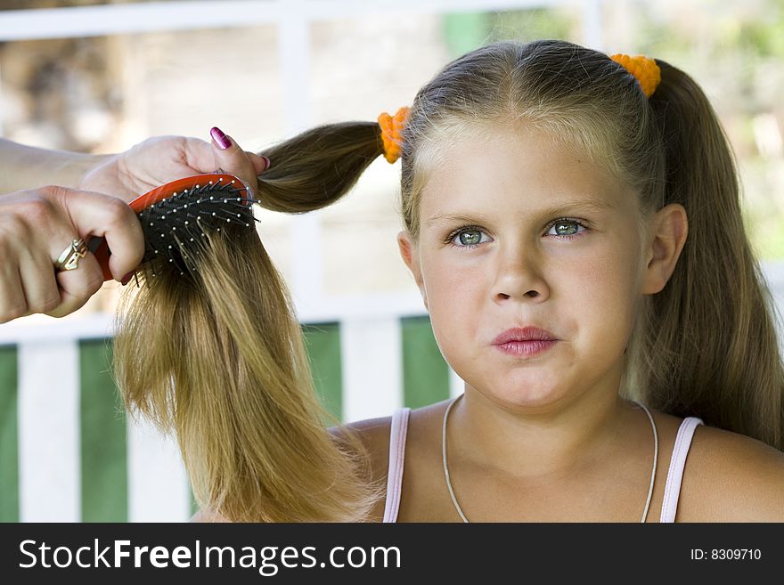 Little blond long hair girl has haircare by stylist.