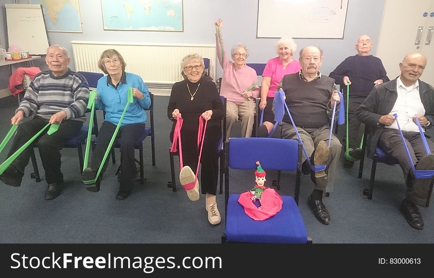 Group of senior citizens exercising with resistance bands in chairs. Group of senior citizens exercising with resistance bands in chairs.