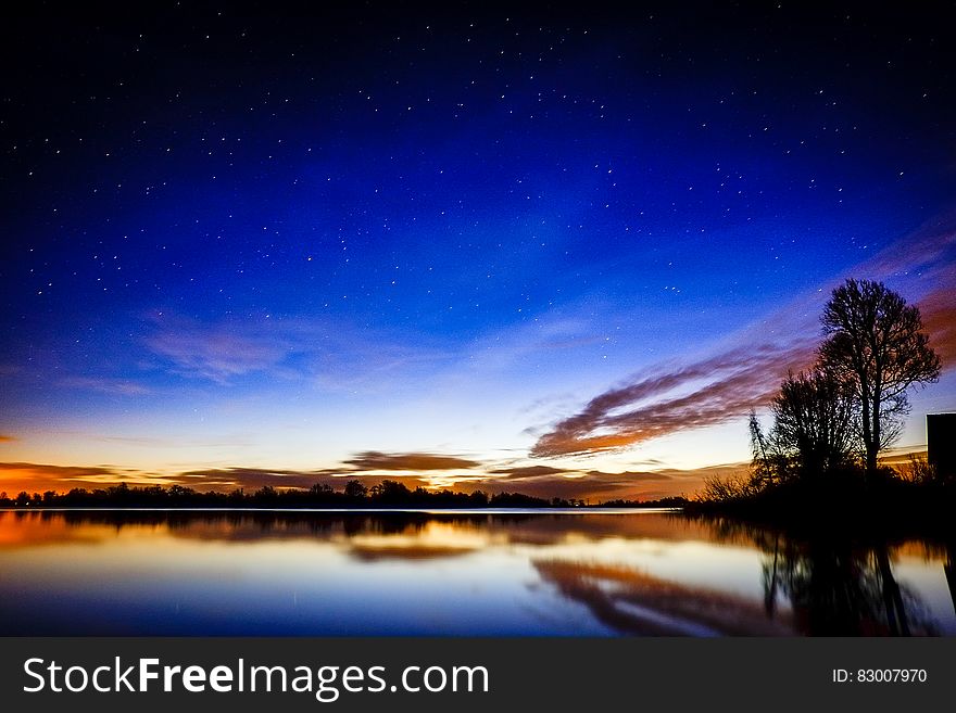 Sunset over reflecting lake with stars in sky. Sunset over reflecting lake with stars in sky.