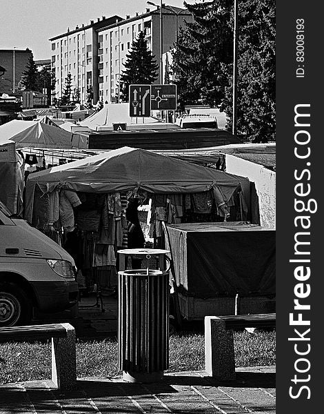 Tents of street fair in urban park in black and white.