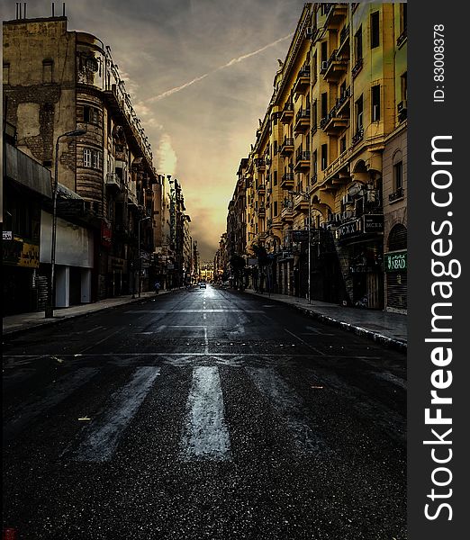 Black Asphalt Road Between Brown City Building Under White Skies during Daytime