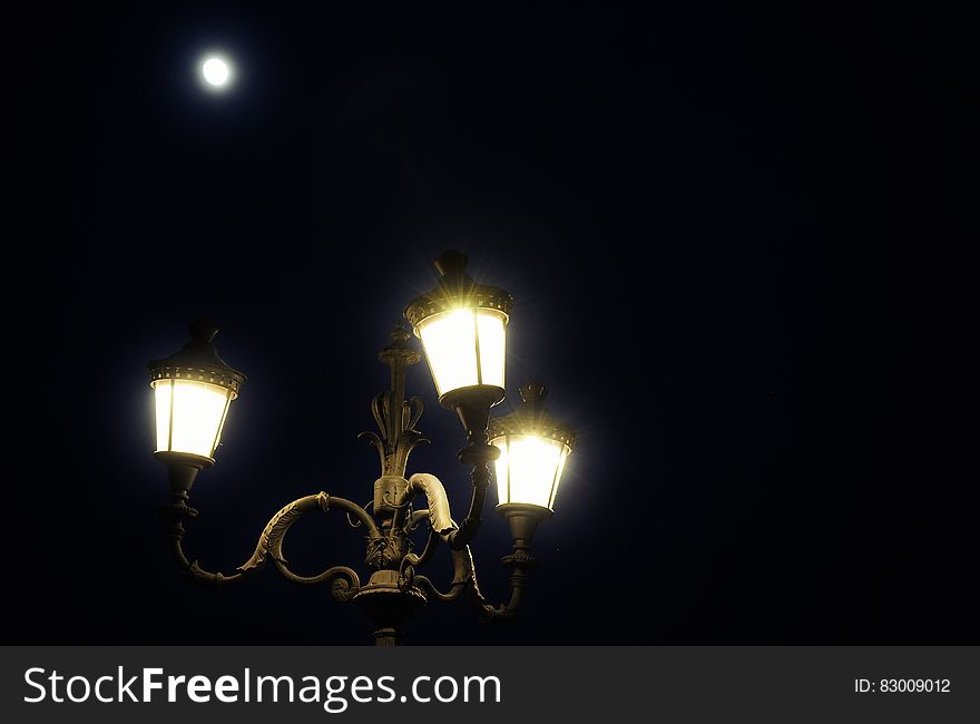 Close up of streetlamp illuminated against night sky with full moon. Close up of streetlamp illuminated against night sky with full moon.