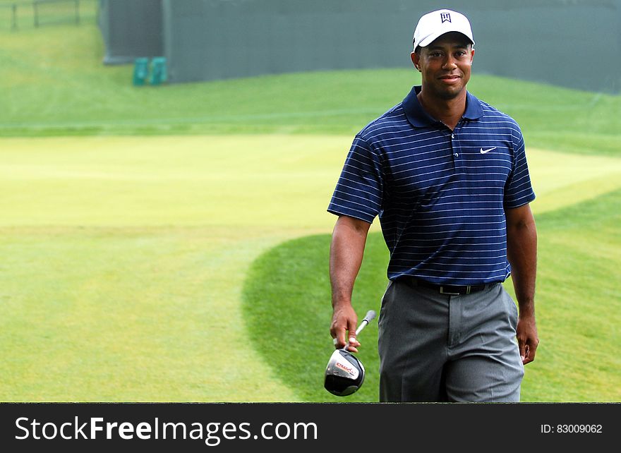 Tiger Woods walking in golf course carrying club. Tiger Woods walking in golf course carrying club.