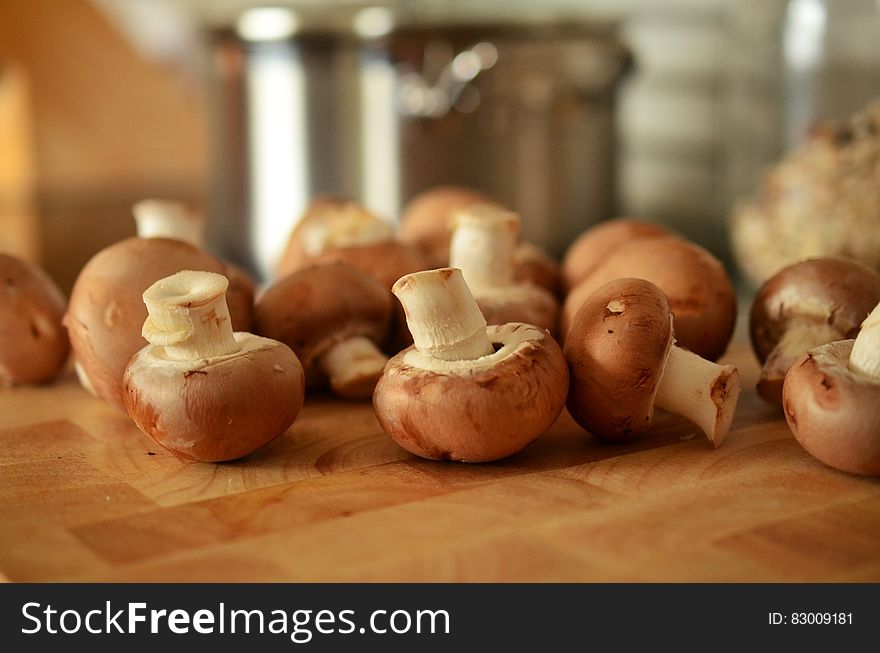 Whole fresh mushrooms on kitchen cutting board.