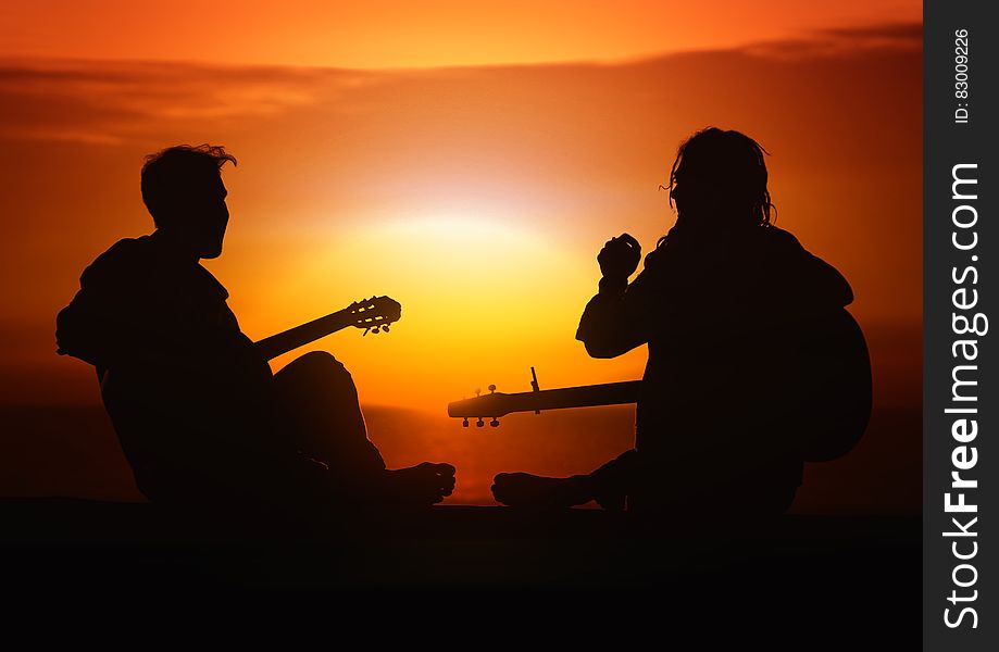 Silhouette of friends playing guitar at sunset. Silhouette of friends playing guitar at sunset.