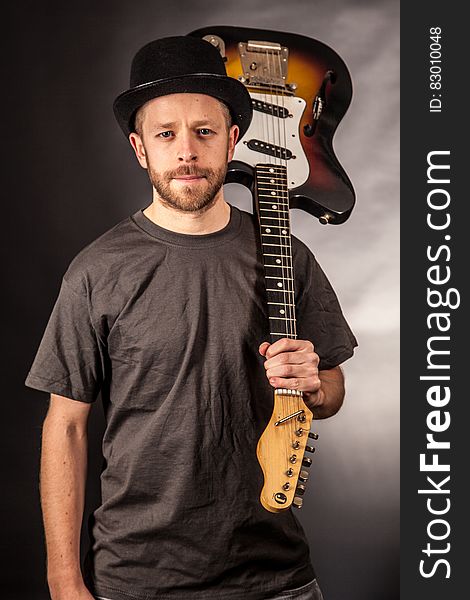 Man in Black T Shirt Holding Electric Guitar Upside Down