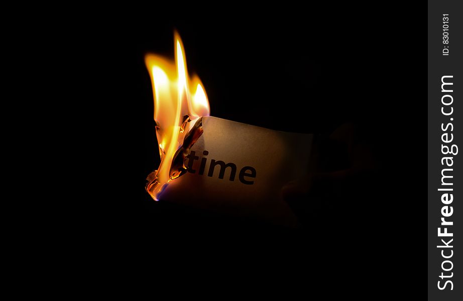 A piece of paper with the word 'time' burning up in flames. A piece of paper with the word 'time' burning up in flames.