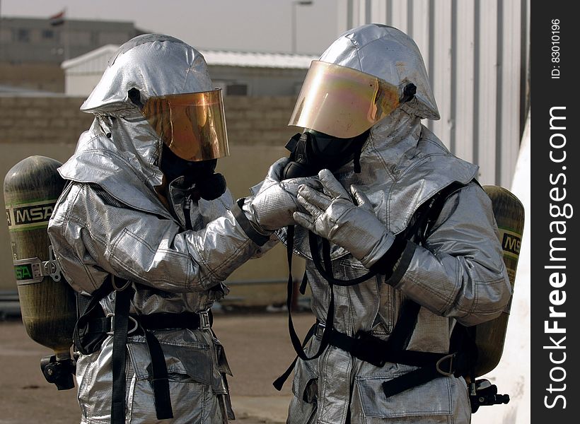 Two firemen in protective suits with gas masks, oxygen bottles and helmets. Two firemen in protective suits with gas masks, oxygen bottles and helmets.