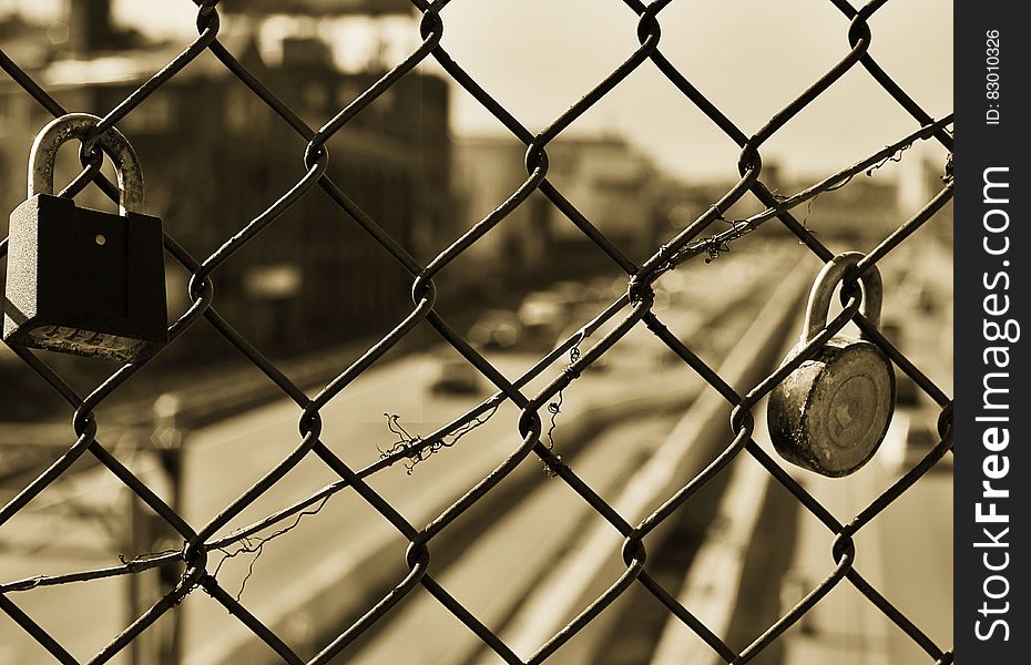 A close up of a fence with locks hanging from it.