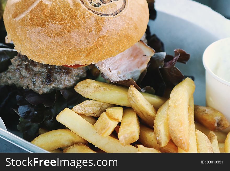 A close up of a burger with fried potatoes. A close up of a burger with fried potatoes.