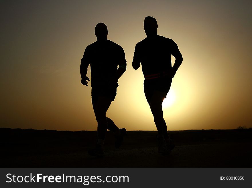 The silhouettes of two runners against the sky. The silhouettes of two runners against the sky.