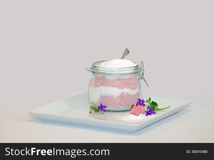 Dessert parfait with whipped cream in glass jar on white plate.