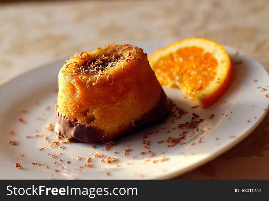 Close up of orange crumb cake on plate with slice of orange.