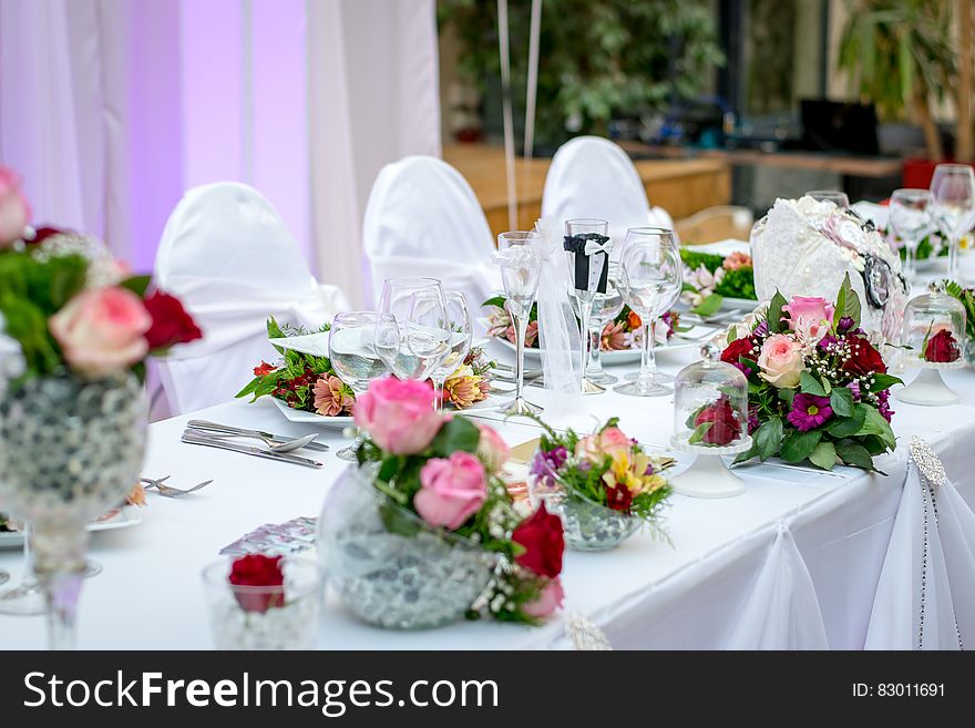 Formal banquet table with white linens and flowers decorated for wedding. Formal banquet table with white linens and flowers decorated for wedding.
