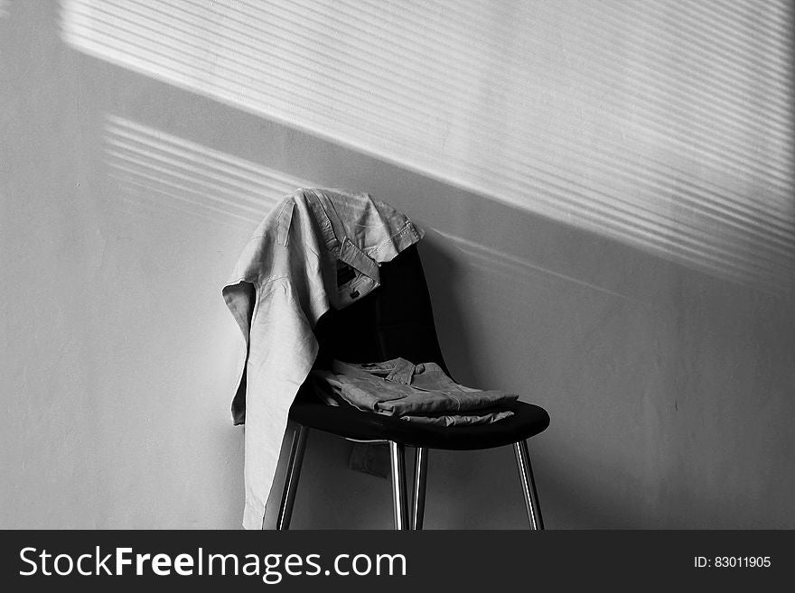 Clothes on chair in room in black and white.