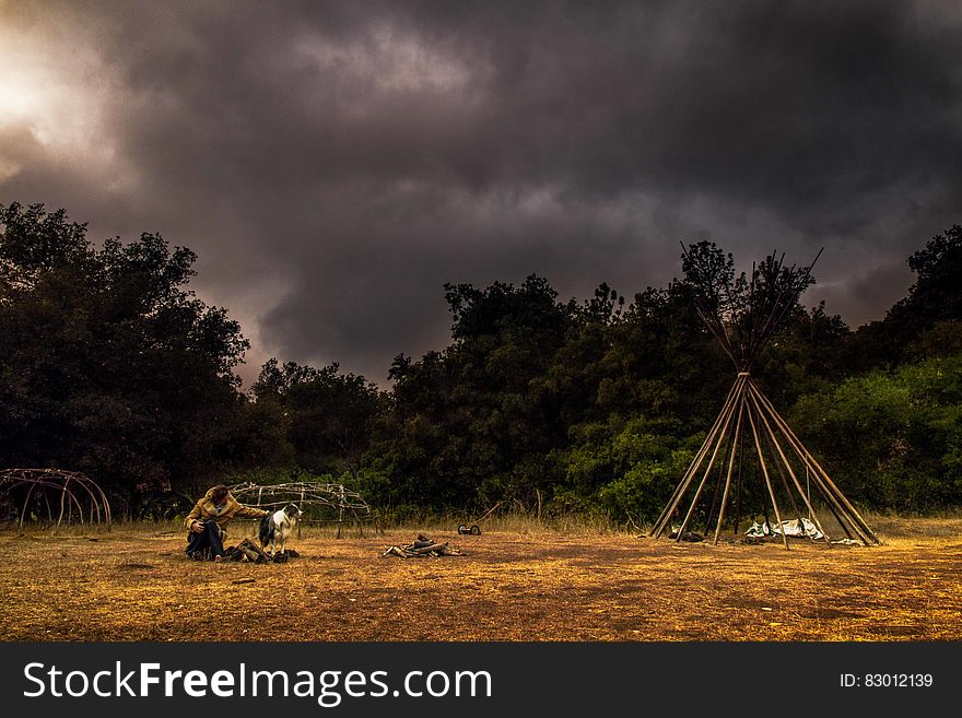 Camper in field under stormy skies.