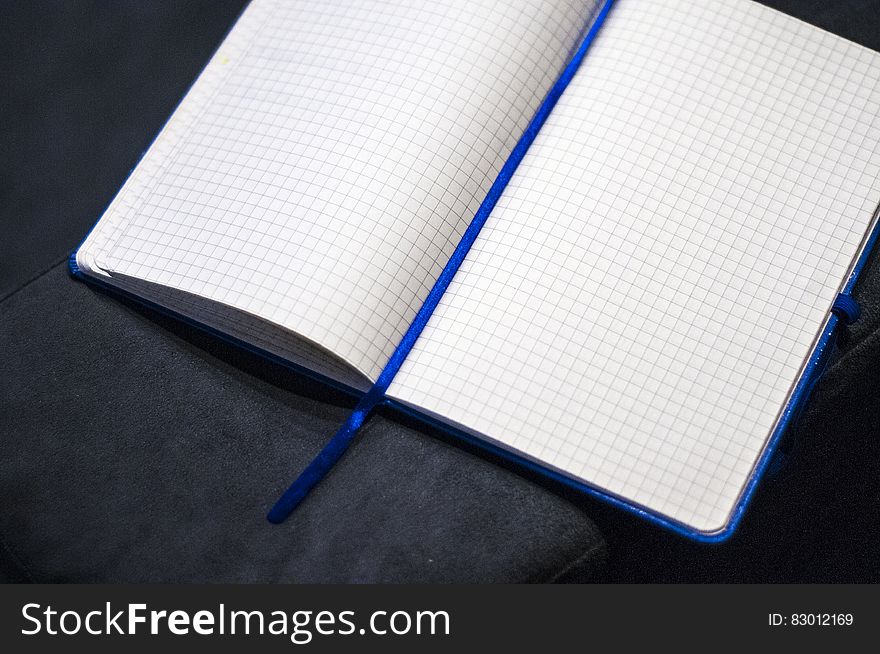 Blank open square ruled notebook lying on dark surface.