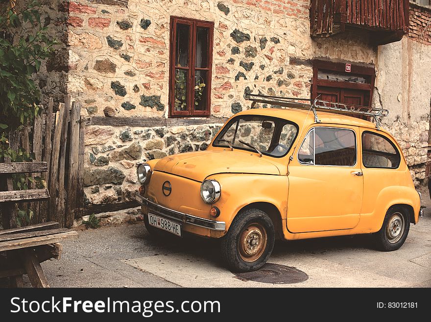 Yellow Nissan Classic Car Beside Gray Beige Concrete Building