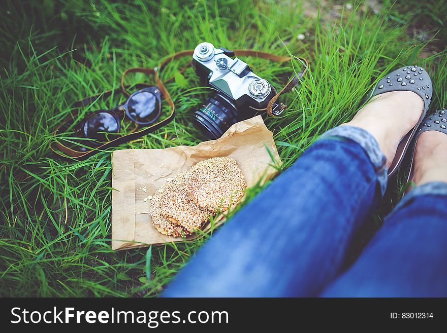 Girl resting on green grass with cookies and camera