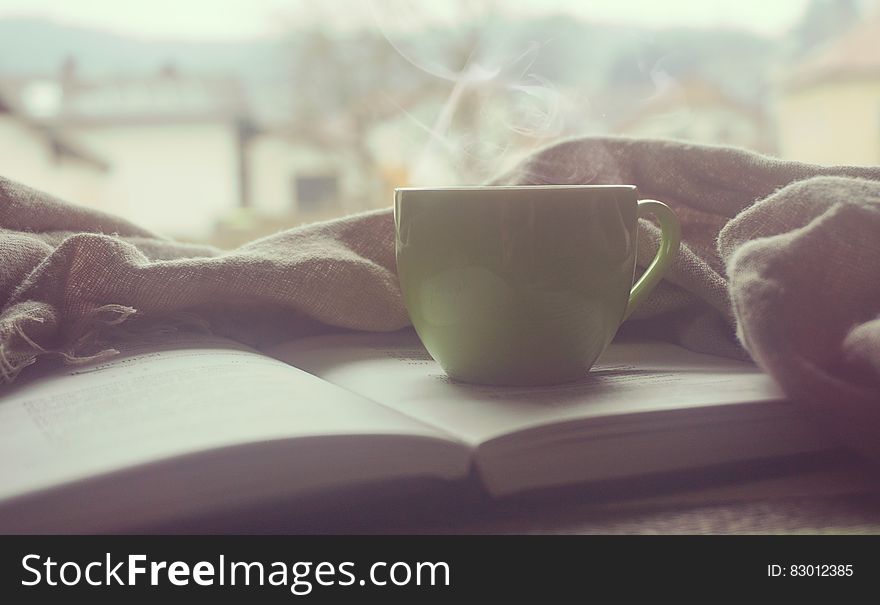 White Hot Mug on Book Near Linen