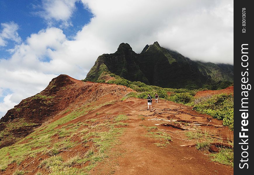 Hikers walking on red hills leading up to mountains. Hikers walking on red hills leading up to mountains.