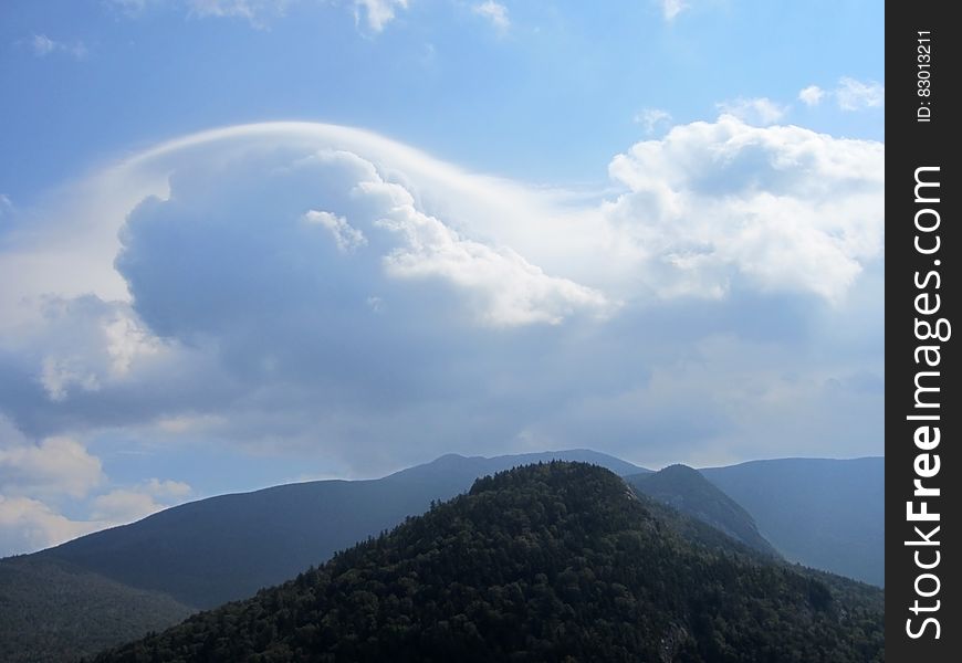 A cloud formation on blue skies over a mountain range. A cloud formation on blue skies over a mountain range.