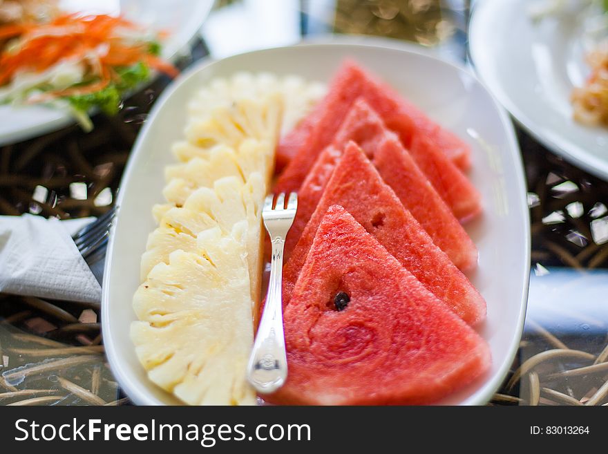 Sliced Watermelon and Pineapple Fruit With Stainless Steel Fork Placed on White Ceramic Rectangular Plate