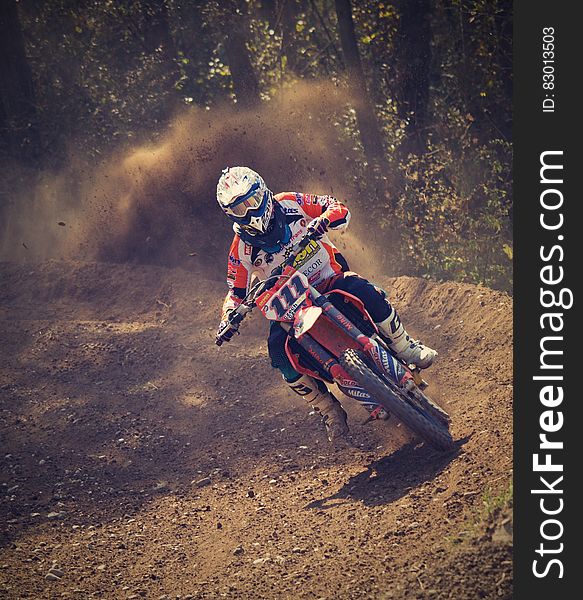 Man in White and Orange Motocross Overall Riding His Motocross Dirt Bike during Daytime