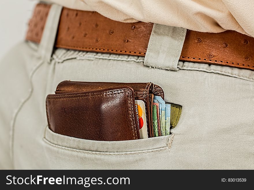 Brown leather wallet in man's pants pocket. Brown leather wallet in man's pants pocket.