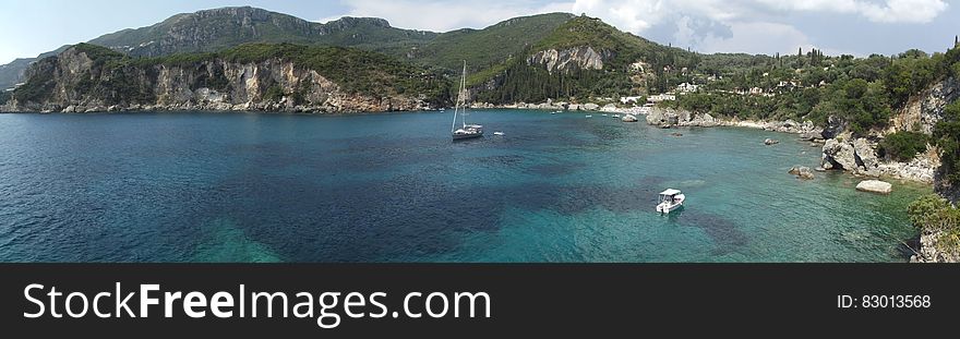 Boats on Ocean Near Gray and Green Mountains during Daytime