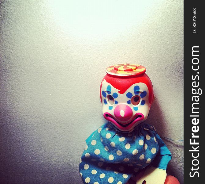 Close up of clown doll against white wall.