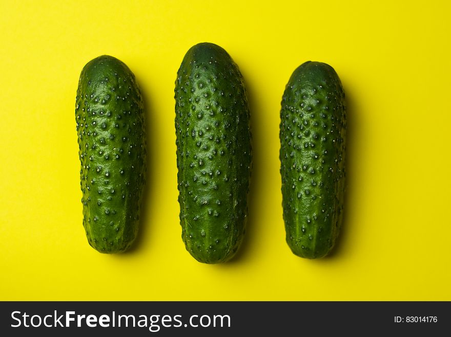 Close up of whole green cucumbers on yellow background.