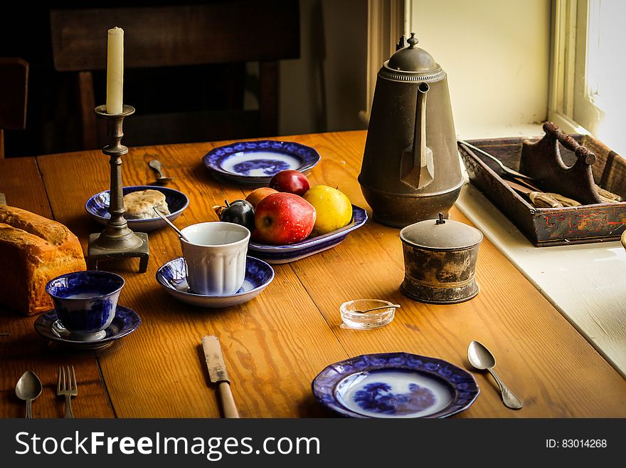 Blue and White Ceramic Plate Next to Apple Fruit and Brown Tea Pot