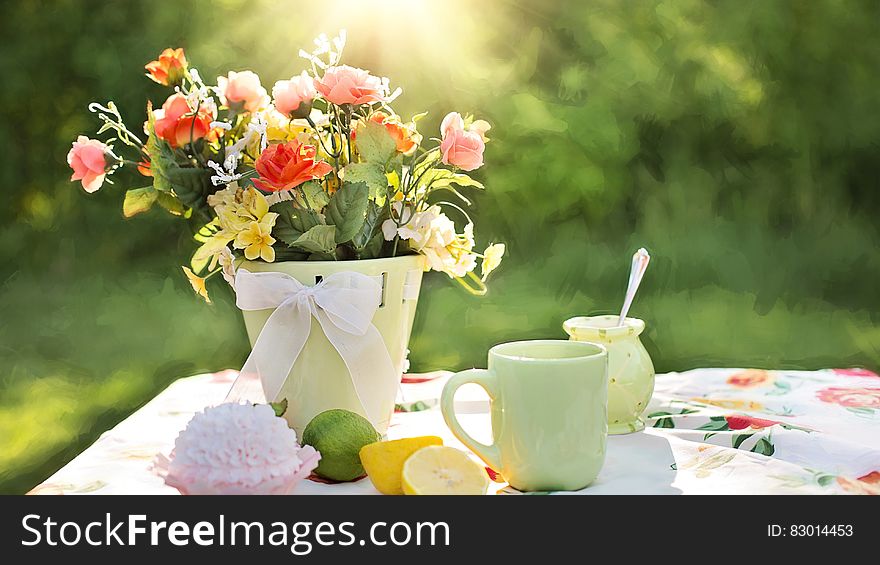 Assorted Flowers on Container Beside Mug on Table