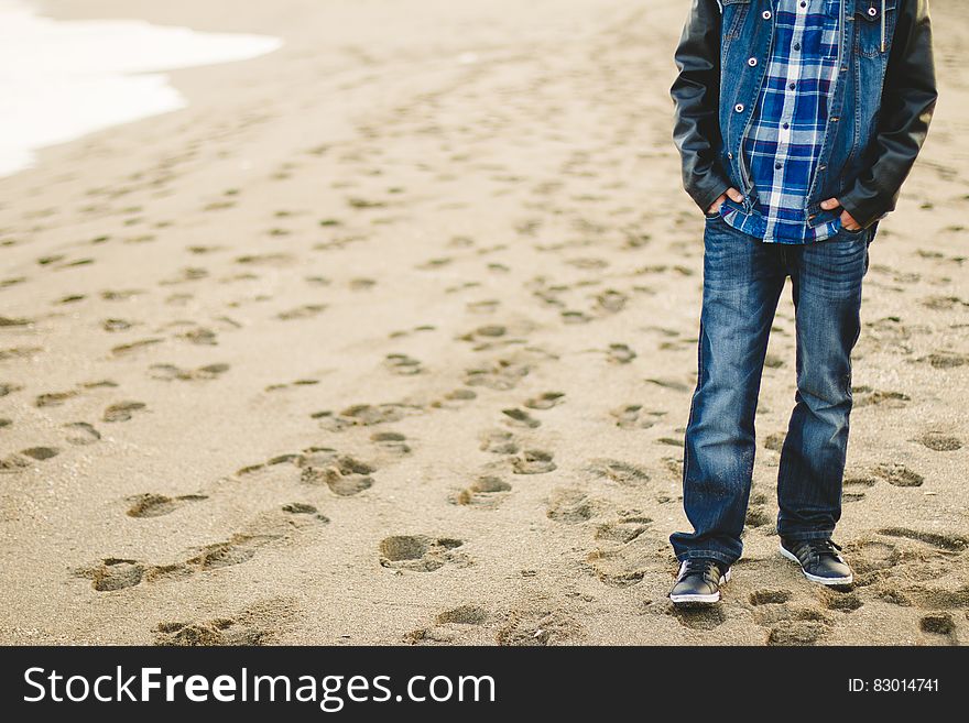 A casually dressed man standing on a sandy beach. A casually dressed man standing on a sandy beach.