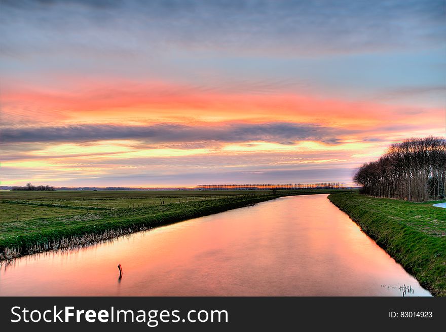 Sunset over green fields along river banks in countryside. Sunset over green fields along river banks in countryside.