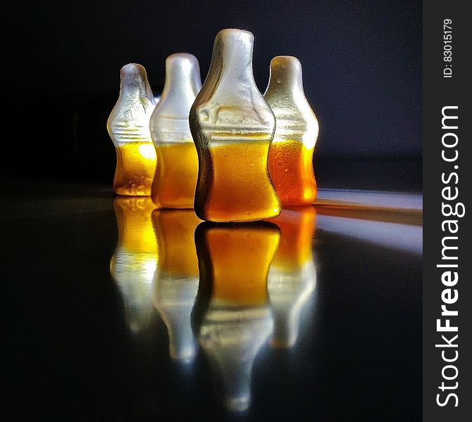 Close up of gummy cola candies reflecting on black.