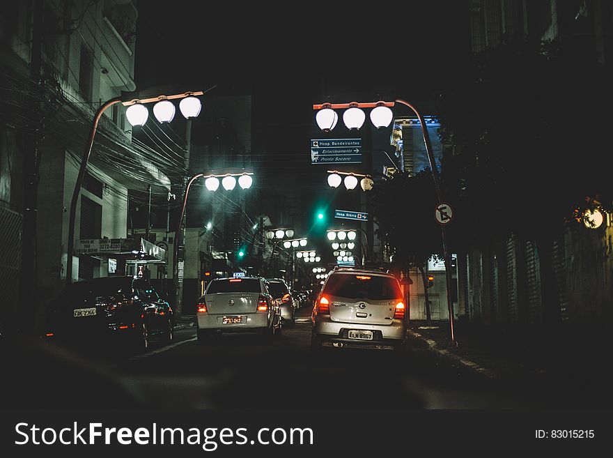 A view of a street at night with cars and streetlights hanging over. A view of a street at night with cars and streetlights hanging over.