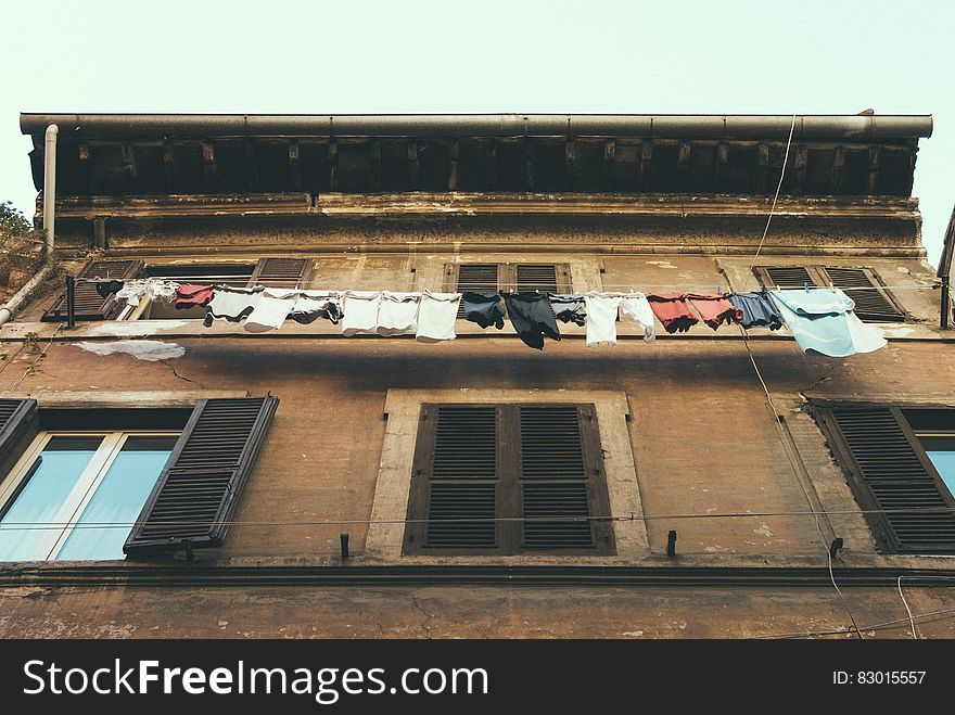 Hanging Clothes and Pants Beside Brown Building