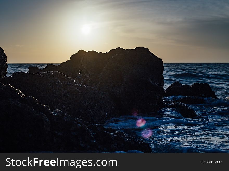 Black Stones on Sea Side during Sunset