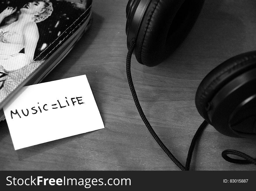 Headphones on a table and a message music equal life on a card next to a case with a picture of Marilyn Monroe. Headphones on a table and a message music equal life on a card next to a case with a picture of Marilyn Monroe.