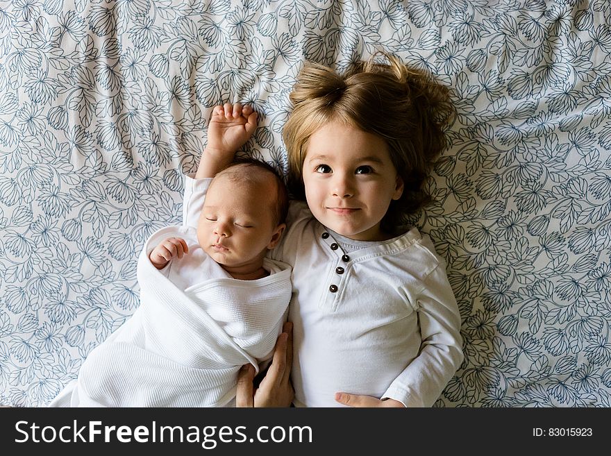 A young boy and his baby brother lying on a bed. A young boy and his baby brother lying on a bed.