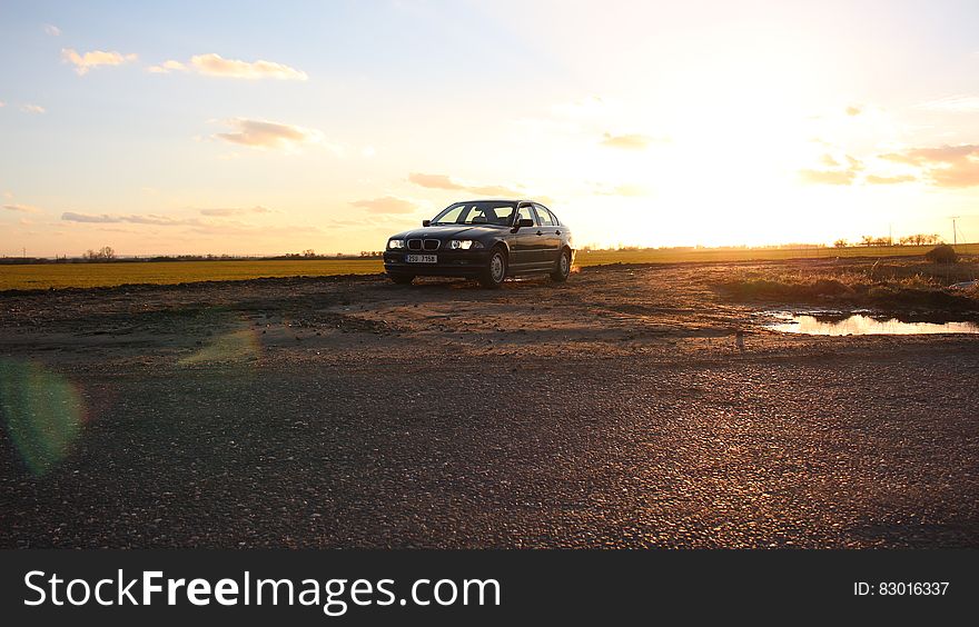 A car parked next to a field at sunset. A car parked next to a field at sunset.