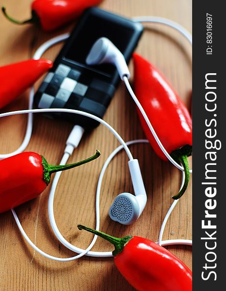 A portable music player with headphones and red chili peppers. A portable music player with headphones and red chili peppers.